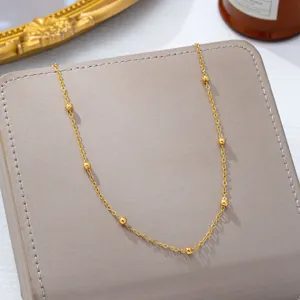 Detailaufnahme der goldenen Perlenkette, zartes Metallaccessoire für Strand und Sommer.