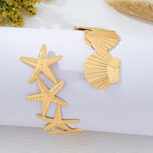 Detailaufnahme des goldenen Seestern- und Muschel-Armreifs, ideal für den Strandurlaub.