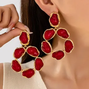 Primo piano dettagliato di orecchini statement in stile barocco vintage rosso scuro e oro.