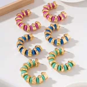 Chunky C-shaped hoop earrings featuring gold textured metal and colorful beaded design.