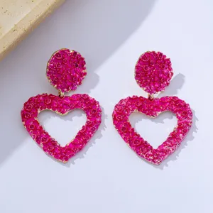 Detailed view of trendy exaggerated textured hollow heart earrings in bright pink.