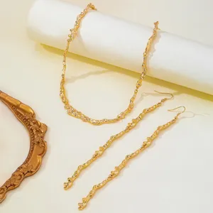 Detailed view of irregular molten texture gold metal necklace and long dangle earrings.