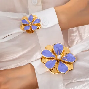 Detail shot of golden purple enamel flower brooch cuff decoration, elegant floral charm.