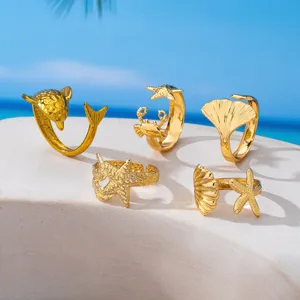 Vista detallada de anillos dorados con temática marina de delfín, cangrejo y estrella.