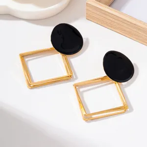 Détail de boucles d'oreilles géométriques en métal creux multicouche avec un top noir.