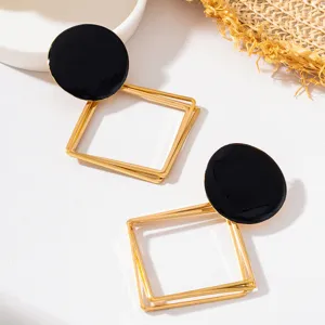 Gros plan détail de boucles d'oreilles pendantes géométriques élégantes en émail noir.