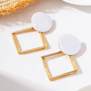 Vue de détail de boucles d'oreilles en métal géométrique émaillé blanc rapproché.