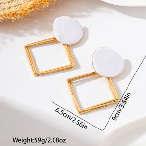 Boucles d'oreilles pendantes email blanc et metal dore geometrique detail en vue.