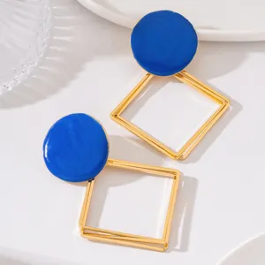 Gros plan détaillé de boucles d'oreilles géométriques creuses dorées et émail bleu raffiné.