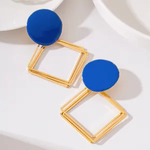 Gros plan détaillé de boucles d'oreilles géométriques dorées avec émail bleu rond.