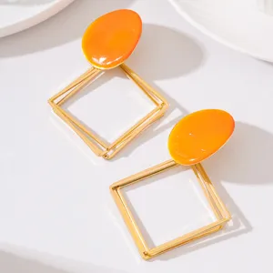 Boucles d'oreilles pendantes géométriques creuses en métal avec émail orange minimaliste.
