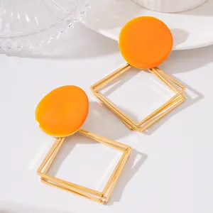 Découvrez ces élégantes boucles d'oreilles géométriques dorées avec pendentif orange.