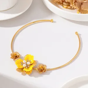 Detailed closeup shot of a golden open choker featuring a yellow enamel flower and pearl decor.
