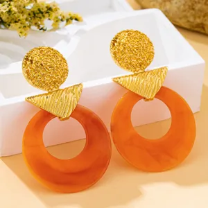 Boucles d'oreilles créoles en résine ambrée vintage avec design géométrique doré texturé.