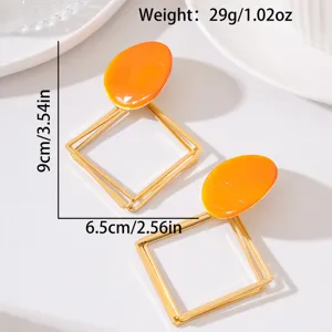 Élégantes boucles d'oreilles géométriques longues avec émail orange vif et monture dorée.