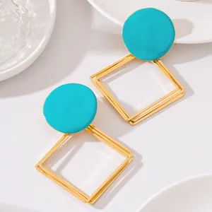 Gros plan détaillé de boucles d'oreilles émail rondes turquoise et géométriques or.