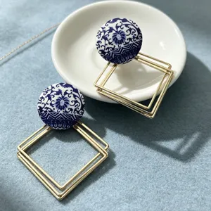 Boucles d'oreilles pendantes carrées géométriques dorées à motif de porcelaine bleue et blanche.