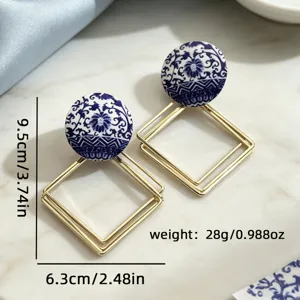 Gros plan détaillé de boucles d'oreilles pendantes géométriques en métal avec motif porcelaine.