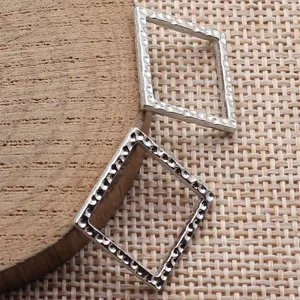 Detailansicht silberner gehämmerter hohler quadratischer Anhänger, geometrisches Basteln.