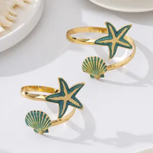 Elegante gouden metalen manchetarmband met blauwe emballage zeester en schelp motieven.