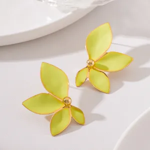 Primo piano dettagliato di eleganti orecchini a lobo con fiori gialli e bordo dorato.