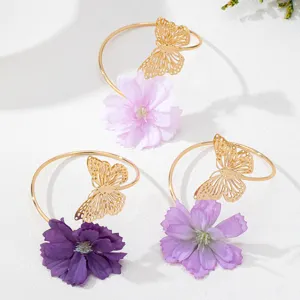 Detailaufnahme des trendigen Sommer-Armbands mit filigranem Schmetterling und zarter Stoffblume.