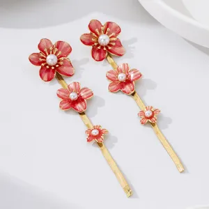Exquisite red enamel flower drop earrings with faux pearls and gold chains. Detailed shot.