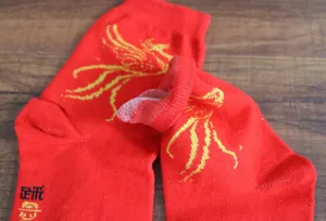 Vue détaillée de chaussettes de mariage rouges en coton avec motif doré et texture douce.