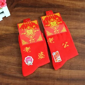 Gros plan de chaussettes de mariage rouges pour couples, en coton, texte brodé festif.