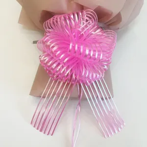 Bright pink pull bow ribbon flower close-up detail for gift wrapping and holiday decoration.