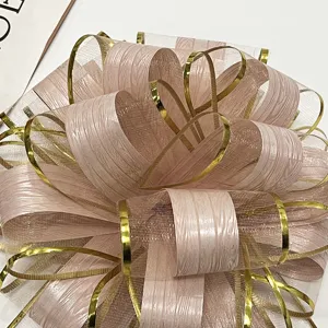 Detailed close-up of large pink mesh pull bow with gold trim and wood grain texture.