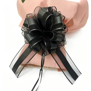 Detailed close-up of extra large black mesh gift ribbon bow with pink wrapping.