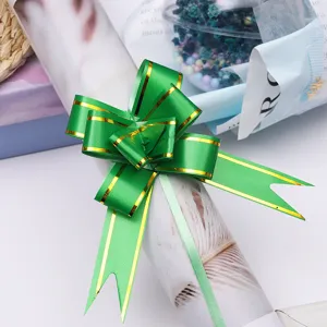 Green pull bow ribbon with gold edge for gift wrapping, flower bouquet decoration detail shot.