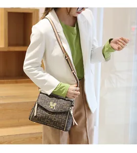Detail view of a fashionable printed monogram crossbody shoulder bag with metal lock.