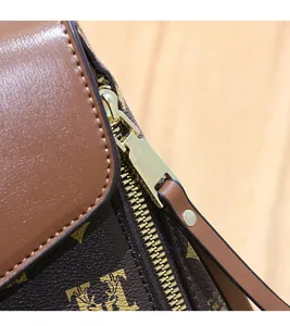 Brown leather shoulder bag detail shot with classic monogram pattern and metal zipper.