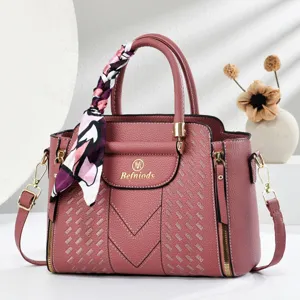 Close-up detail view of the pink embossed leather handbag featuring elegant handle silk scarf.