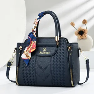 Detailed view of the dark blue embossed leather handbag with chic handle scarf and side zippers.
