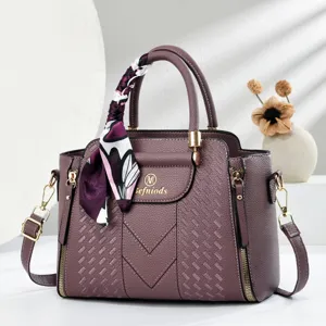Close-up view of textured PU leather handbag with elegant silk scarf and metal lock hardware detail.