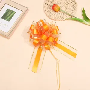 Large orange sheer ribbon bow with gold edge for gift wrapping and holiday party decoration.