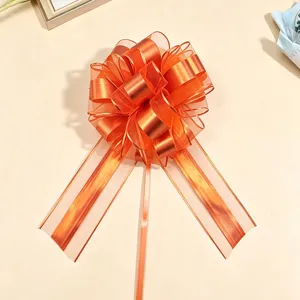 Orange metallic gift wrapping pull bow detail, 3D spherical bow for festive decoration.