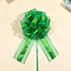 Close up detail shot of a large green gift wrapping pull bow, showcasing texture and bow layers.