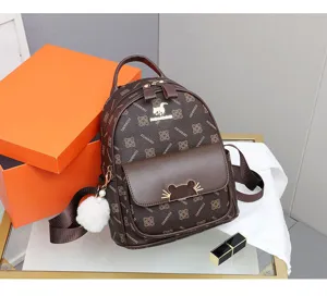 Detailed view of brown monogram fashion mini backpack with cute metal clasp and fluffy charm.
