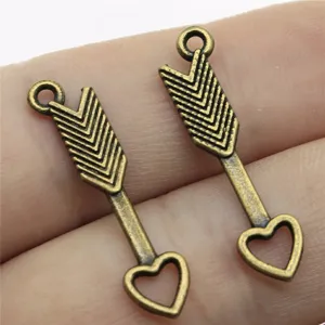 Primo piano dettaglio di ciondoli cuore freccia in lega bronzo antico per gioielli.
