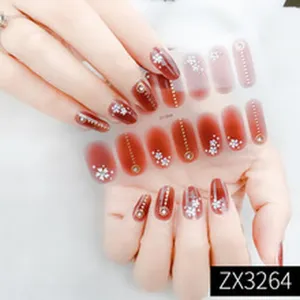 Red gradient press-on nails with white floral patterns and metal studs for stylish manicure.