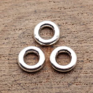 Close-up detail of silver tone round spacer beads and metallic ring connectors for jewelry making.