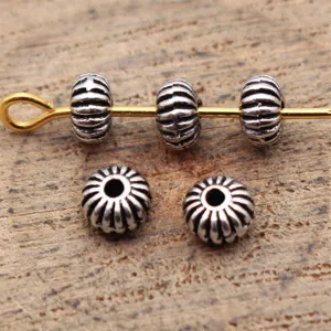 Close-up detail of antique silver ribbed spacer beads, small hole design for jewelry DIY crafting.