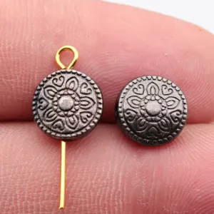 Gros plan détaillé d'une perle intercalaire ronde en métal gravé au motif floral vintage.