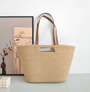 Woven tote bag detail featuring textured straw rope body, brown leather handles and chic rivets.