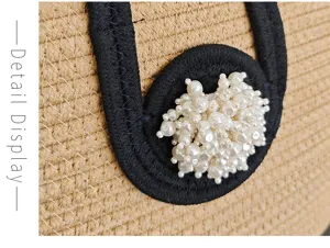 Nahaufnahme einer geflochtenen Strohtasche mit schwarzem Besatz und Perlendekoration.