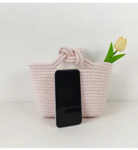 Nahaufnahme der rosa-weißen geflochtenen Seilhandtasche mit einem süßen Knotengriff.
